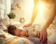 Parent tucking child into bed