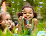 Girls blowing bubbles in garden