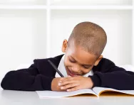 Child happily writing in school book