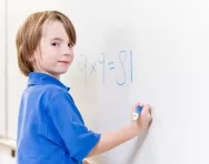 Child writing numbers on whiteboard