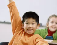 Children putting their hands up in class