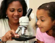 Girl and teacher using microscope