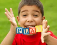 Boy holding blocks spelling 'play'