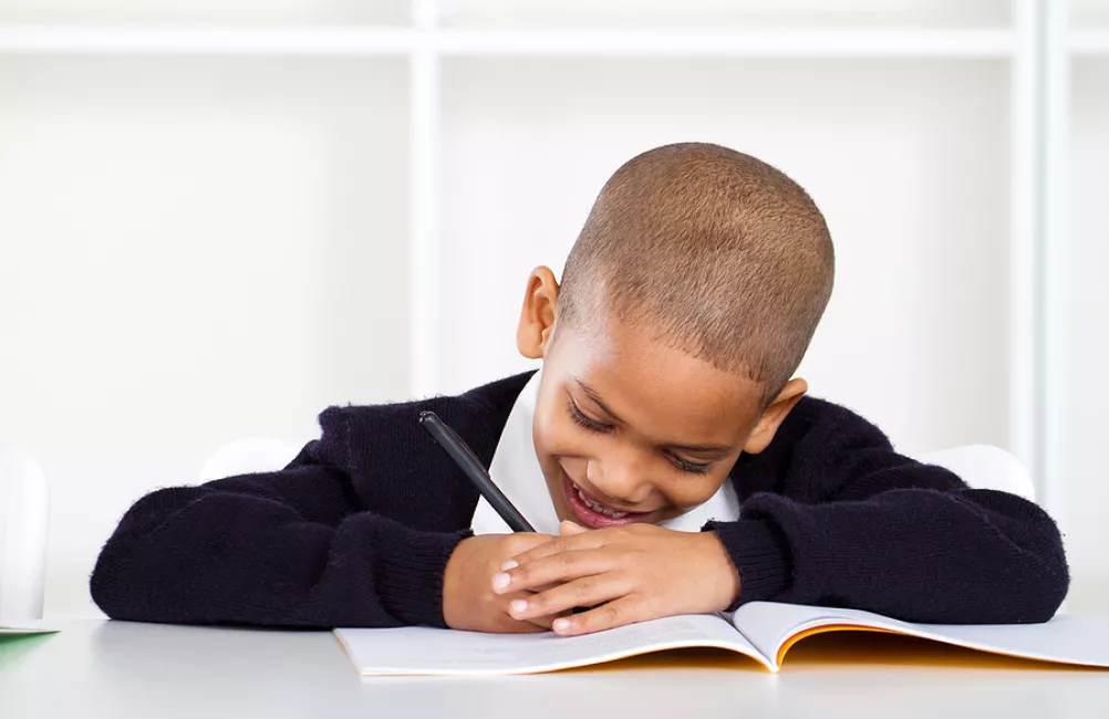 Child happily writing in school book