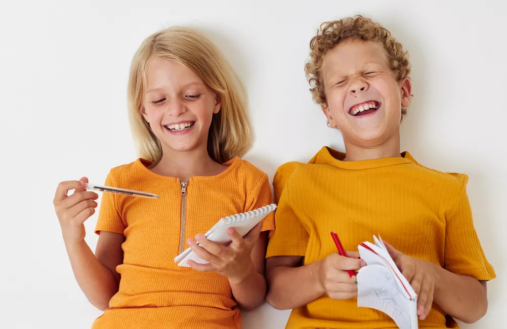 Two children laughing and writing